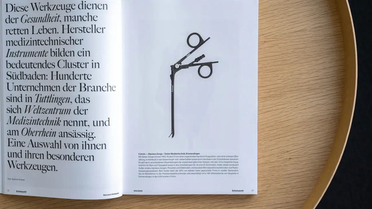 Offenes Magazin auf einem runden Holztisch, links Textseite und rechts eine schwarz-weiße Illustration einer Calvian® Bipolaren Zange