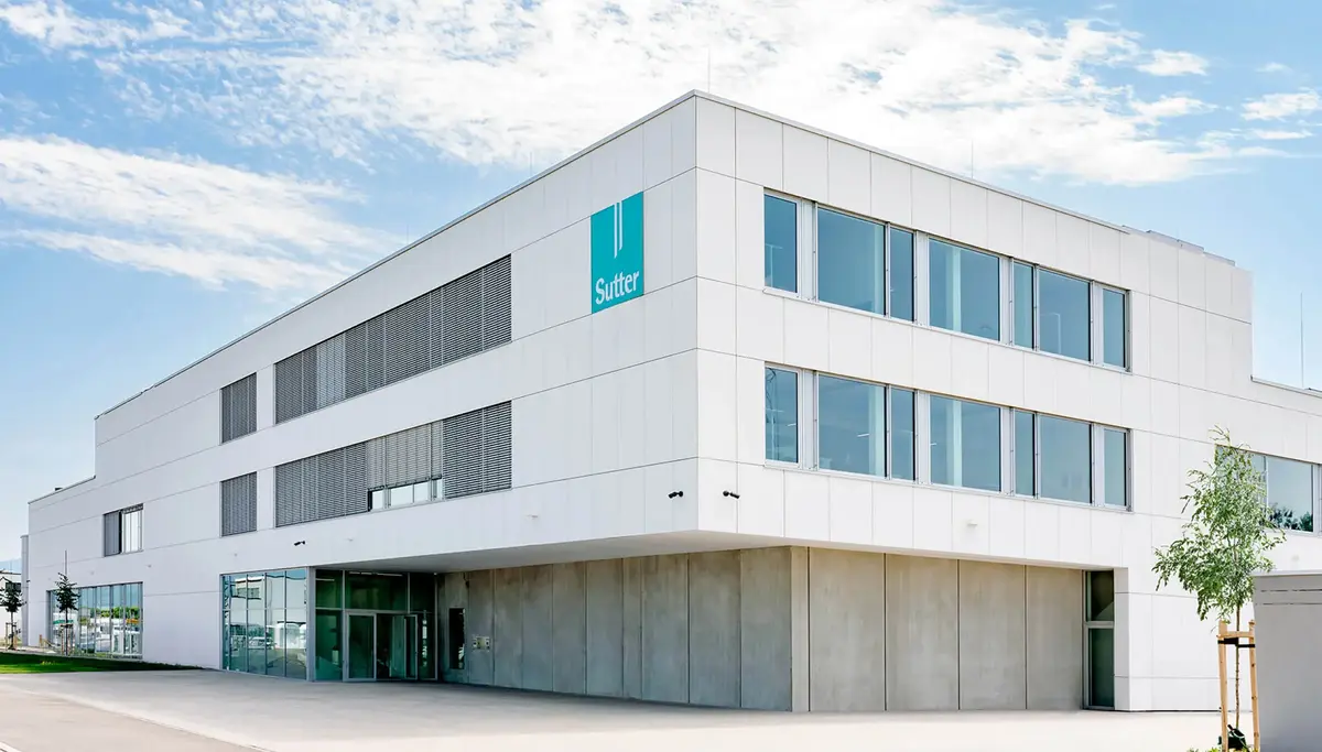 Modernes weißes Gebäude mit großen Fenstern und einzigartigem architektonischem Design. Das zweistöckige Gebäude besitzt ein auskragendes Obergeschoss und geometrische Formen an der Fassade, die den zeitgenössischen Stil unterstreichen.