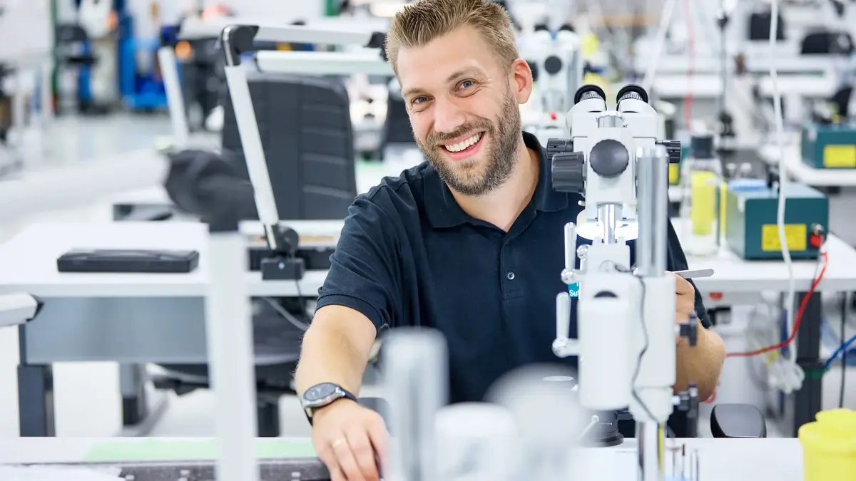 © Jörg Wilhelm Thomas Rietsche, stellvertretender Teamleiter bei Sutter Medizintechnik, bei der Arbeit in der Feinmechanik unter dem Mikroskop – Fokus auf Qualität und Ausbildung.